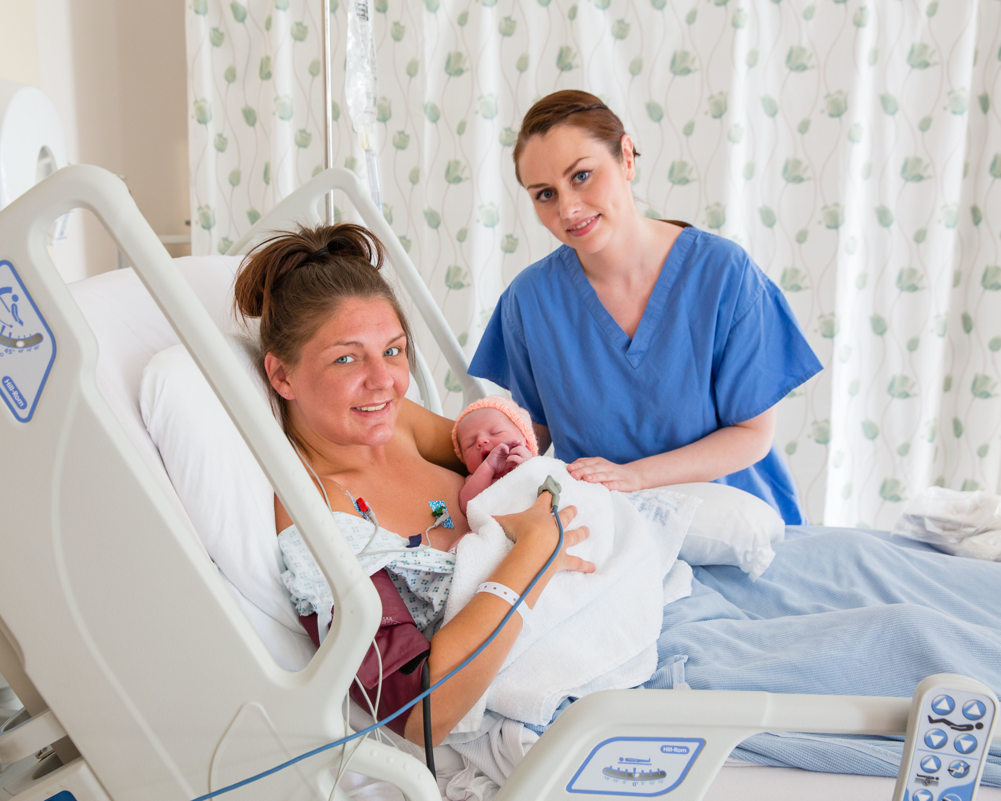 A mother with newborn baby in a hospital bed, with an NHS Scotland member of staff