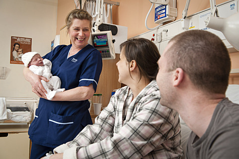 A midwife with new parents and their baby