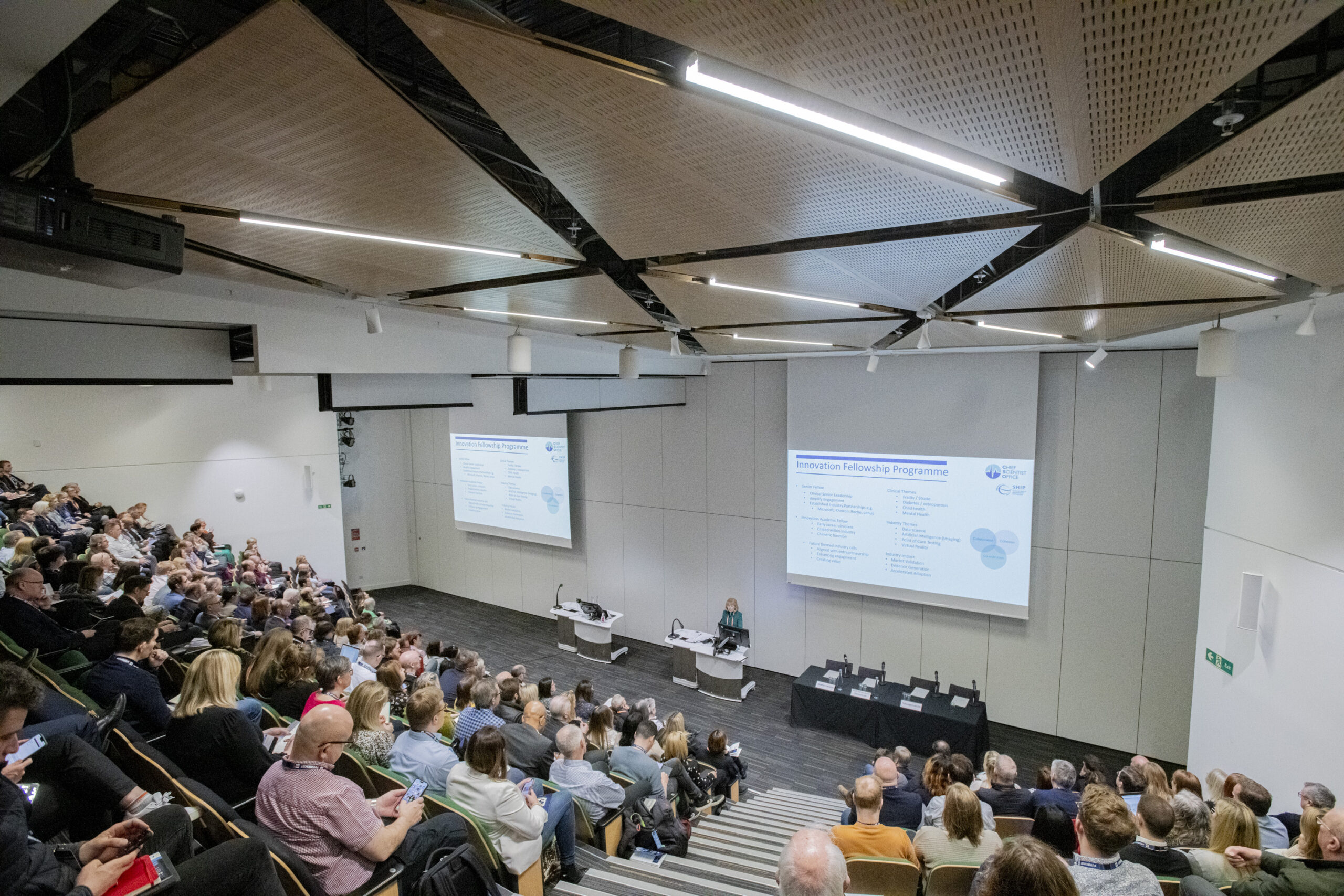 The conference hall of the previous Health and Care Transformation conference in 2024, with Professor Dame Anna Dominiczak presenting to a full auditorium.