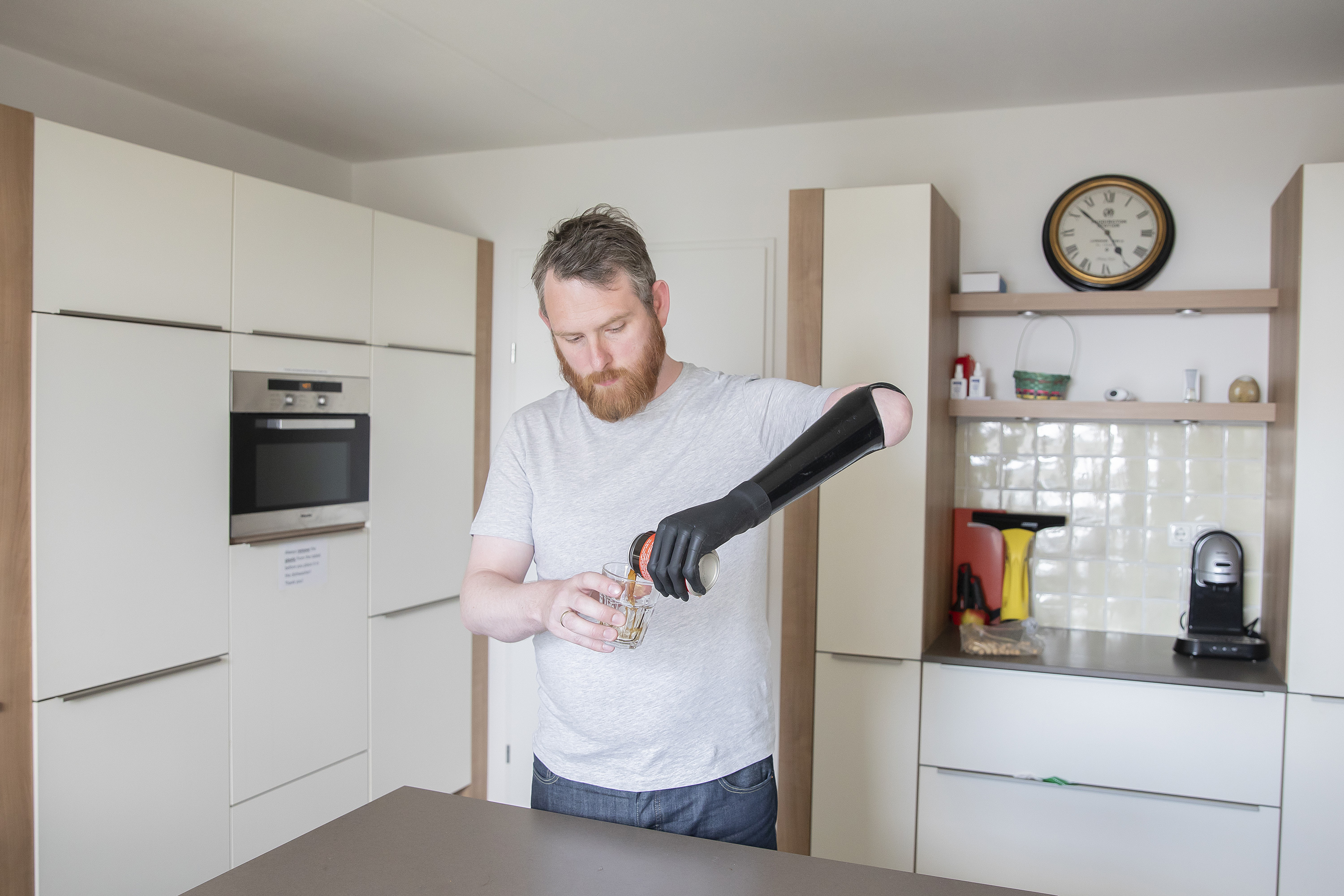 A man pouring a drink in a kitchen using the Touch i-Limb.
