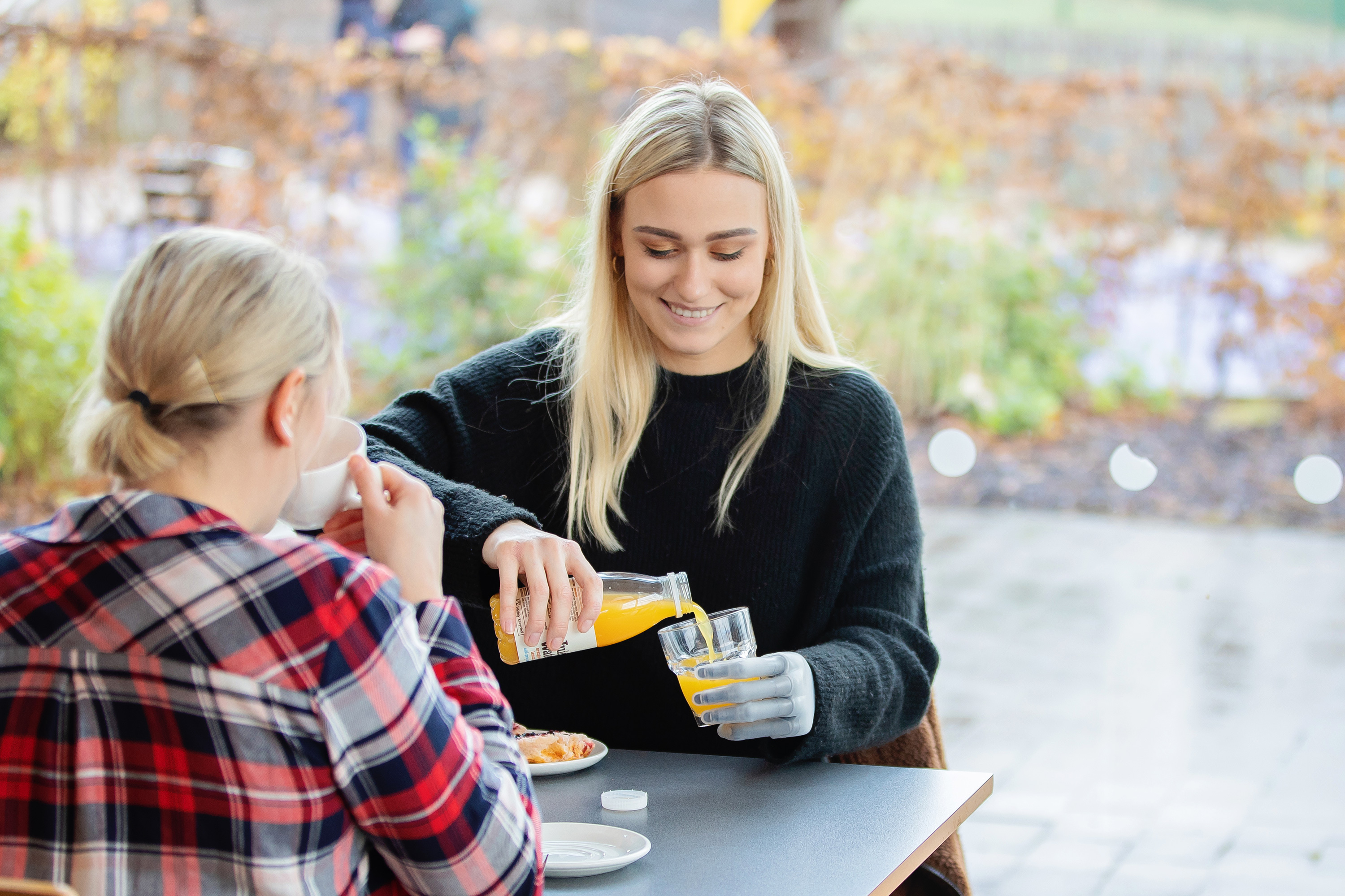 A woman pouring a drink at a cafe using a Touch i-Limb.