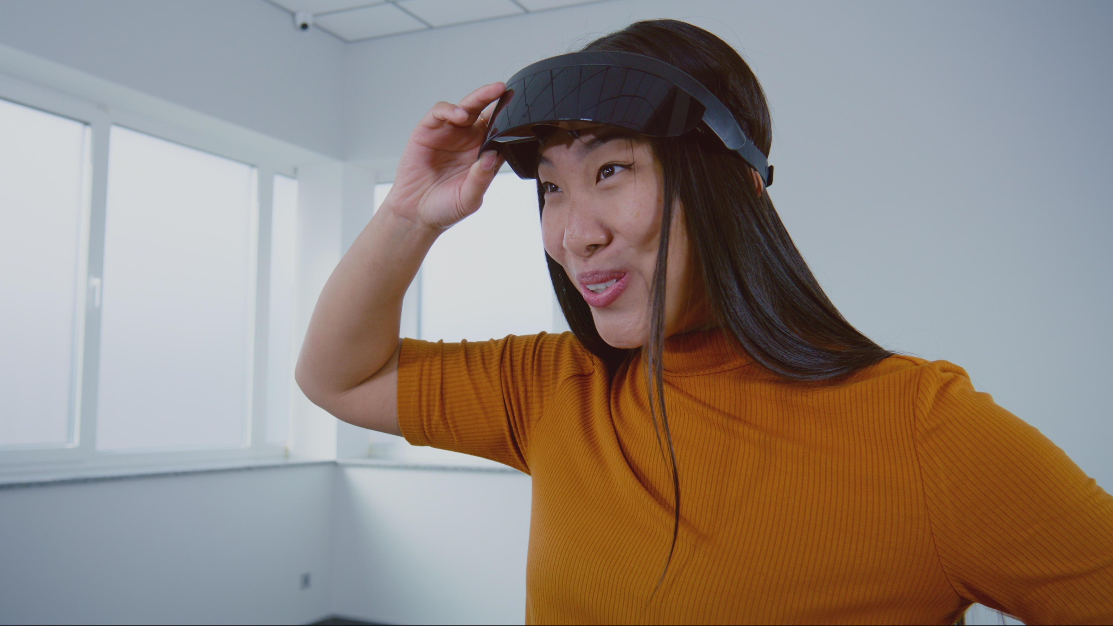 A woman in a yellow jumper using a virtual reality headset.
