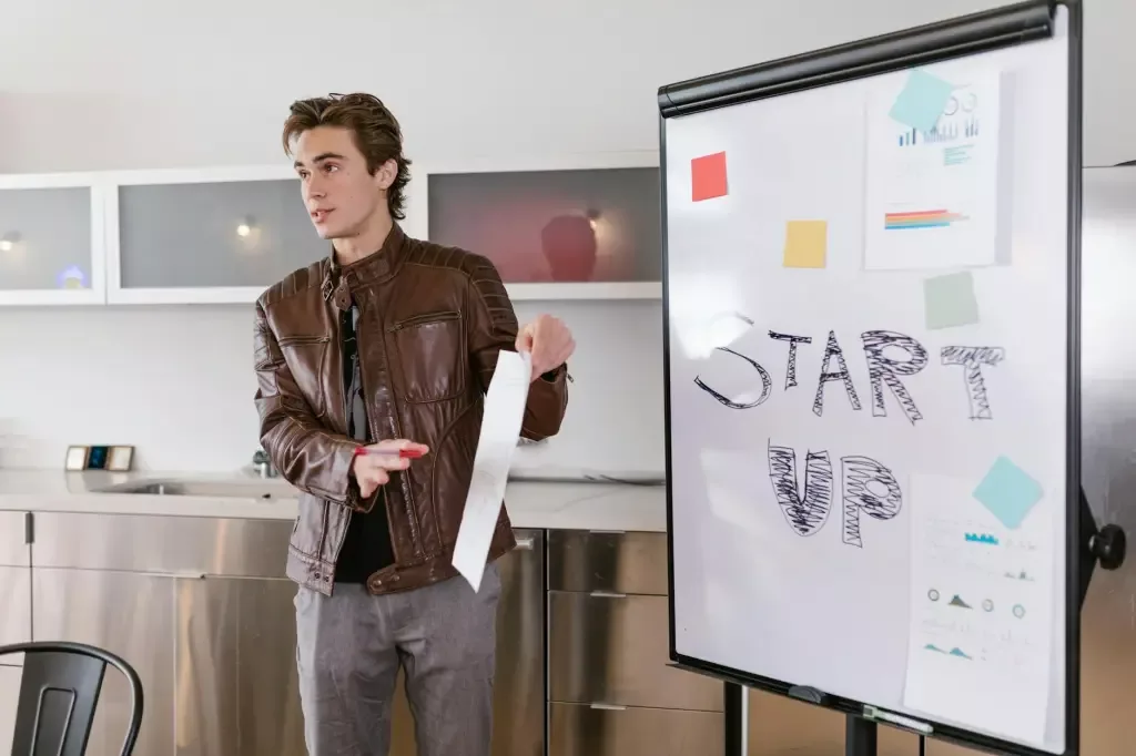 A young man standing in front of a whiteboard giving a presentation.