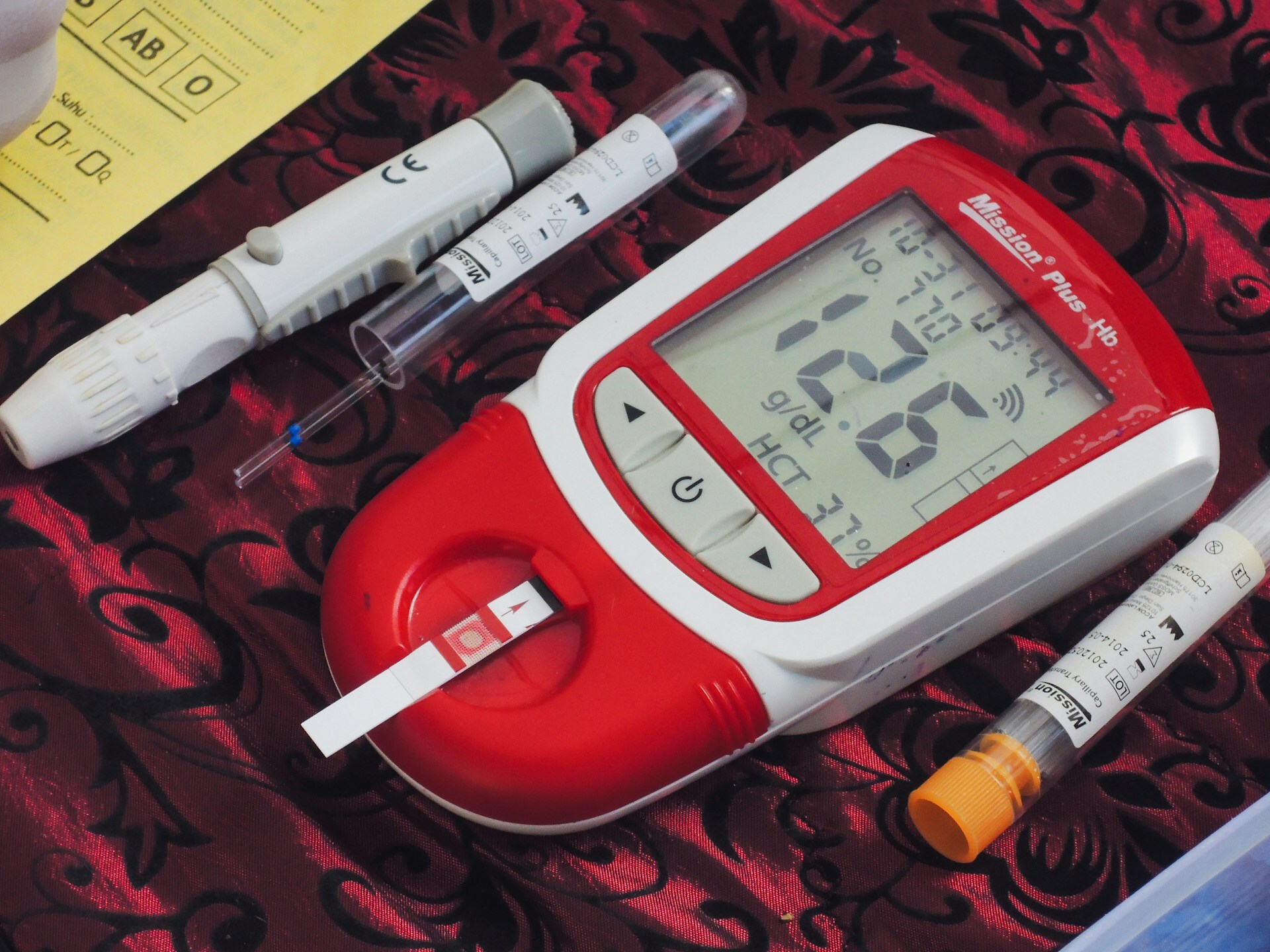 A thermometer. a pen and two sys sat on a table.